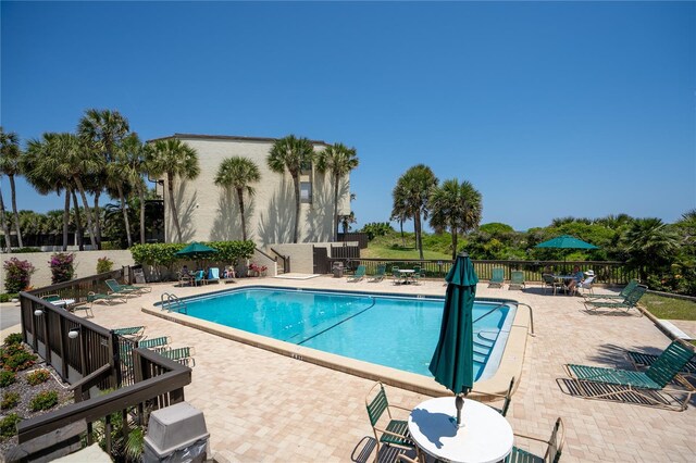 community pool with a patio and fence