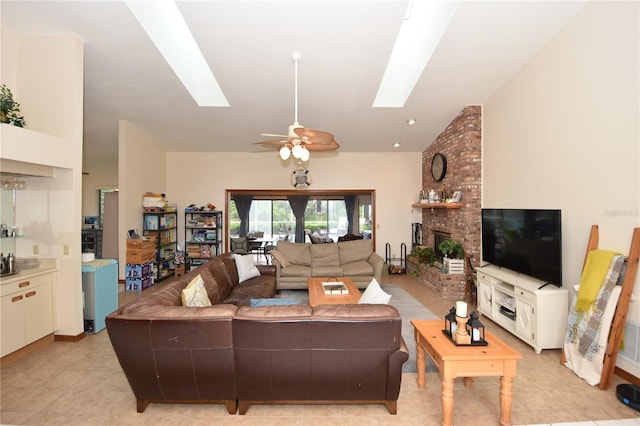 living room with light tile patterned flooring, lofted ceiling with skylight, ceiling fan, and a brick fireplace