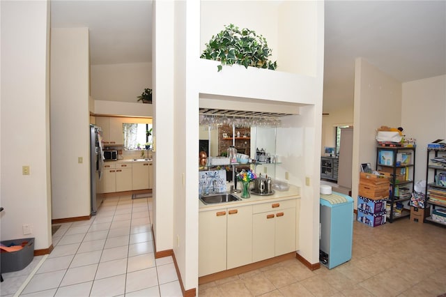 kitchen featuring stainless steel appliances, sink, light tile patterned floors, and high vaulted ceiling