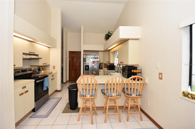 kitchen with kitchen peninsula, high vaulted ceiling, appliances with stainless steel finishes, a wealth of natural light, and light tile patterned floors