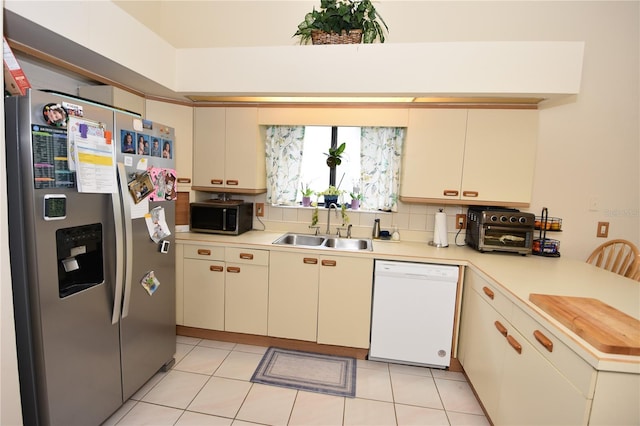 kitchen with sink, stainless steel appliances, backsplash, and light tile patterned floors