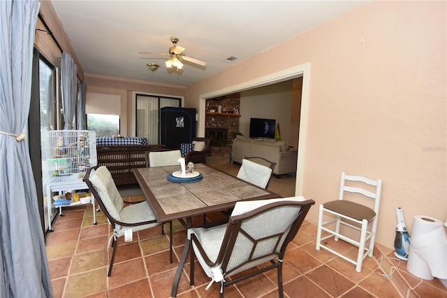 tiled dining space with a fireplace and ceiling fan