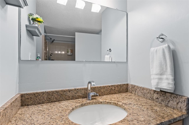 full bathroom with a textured ceiling, a shower, and vanity