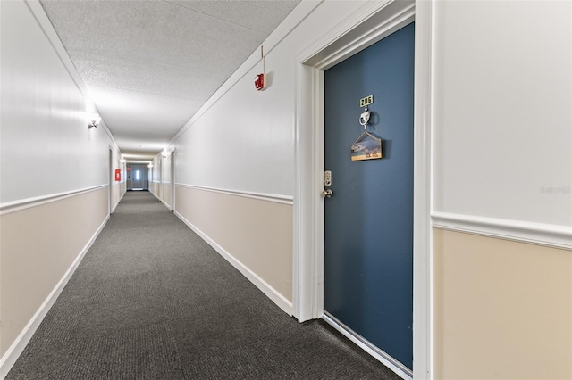 corridor featuring a textured ceiling, carpet floors, and baseboards