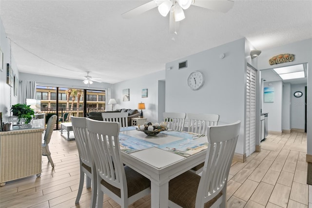 dining area with a ceiling fan, visible vents, a textured ceiling, and wood finish floors