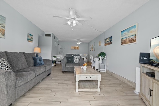 living room with wood finish floors, visible vents, and a ceiling fan