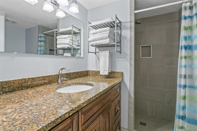 full bathroom with a shower stall, visible vents, a textured ceiling, and vanity