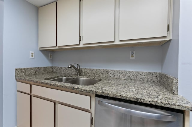 kitchen with light stone counters, white cabinetry, dishwasher, and a sink