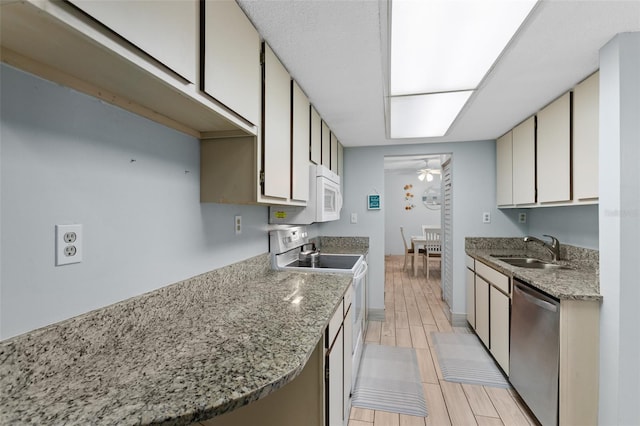 kitchen featuring ceiling fan, light stone counters, white appliances, a sink, and wood tiled floor