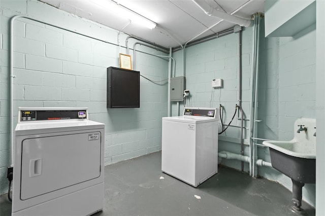 clothes washing area featuring concrete block wall, laundry area, electric panel, and washer and clothes dryer