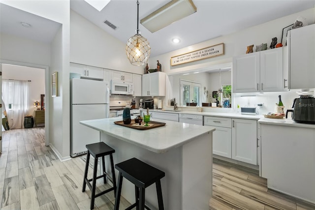 kitchen with decorative light fixtures, white appliances, light hardwood / wood-style flooring, and white cabinets