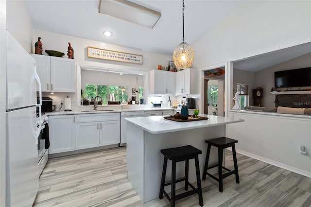 kitchen with white appliances, lofted ceiling, a kitchen breakfast bar, light countertops, and a sink