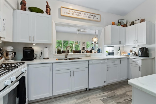 kitchen featuring white appliances, backsplash, a sink, and white cabinets