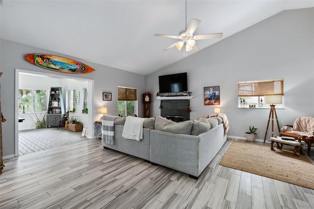 living room with baseboards, high vaulted ceiling, light wood-style flooring, and a ceiling fan