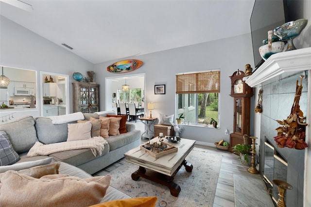 living area featuring vaulted ceiling, light wood finished floors, and visible vents