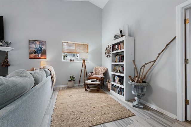 sitting room with high vaulted ceiling, wood finished floors, and baseboards