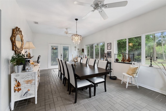 dining room with ceiling fan with notable chandelier, visible vents, baseboards, brick patterned floor, and french doors