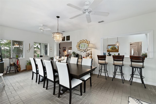 dining space with ceiling fan with notable chandelier, visible vents, and baseboards