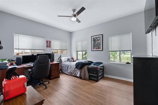 bedroom with light wood-style flooring, multiple windows, baseboards, and ceiling fan