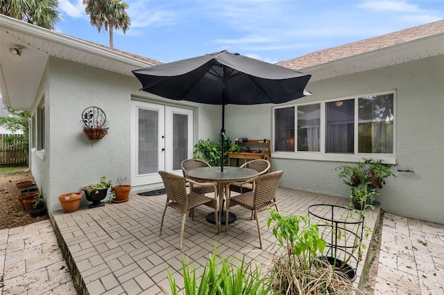 view of patio with french doors, outdoor dining area, and fence