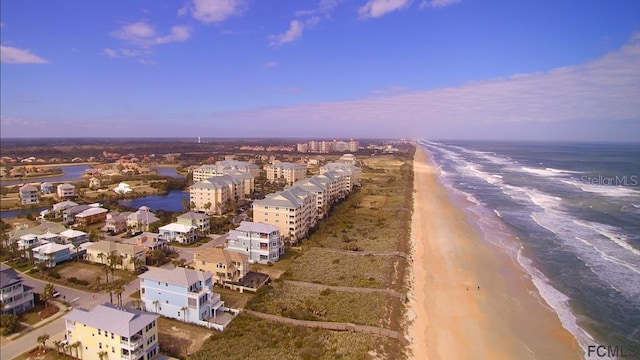 aerial view at dusk featuring a water view and a beach view