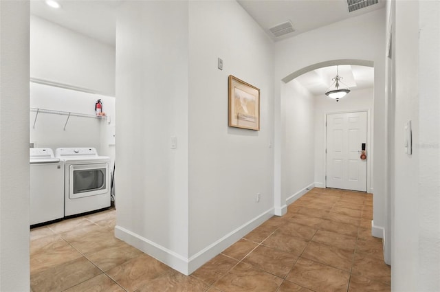 200 Cinnamon Beach Way Unit 122, Palm Coast, FL 32137 - hallway featuring arched walkways, independent washer and dryer, light tile patterned floors, and baseboards