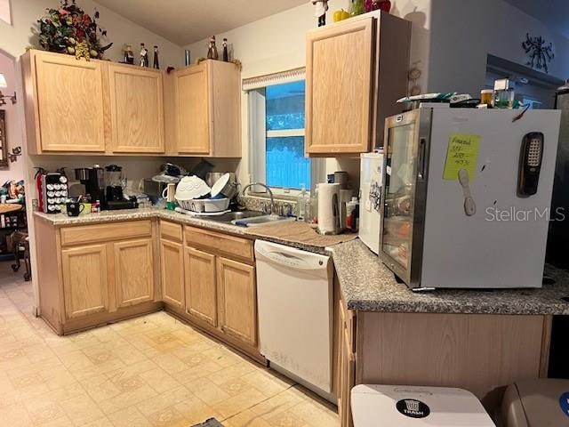 kitchen featuring white dishwasher, light brown cabinets, light tile patterned floors, fridge, and sink