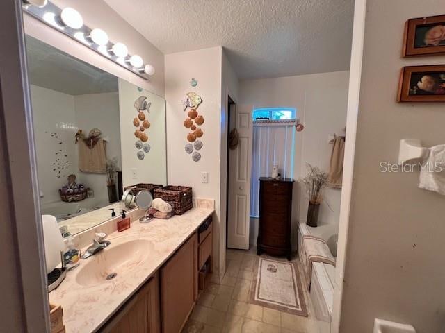 bathroom featuring a textured ceiling, tile patterned floors, and vanity