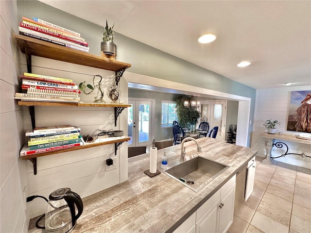 kitchen featuring light tile patterned flooring, sink, french doors, and white cabinetry