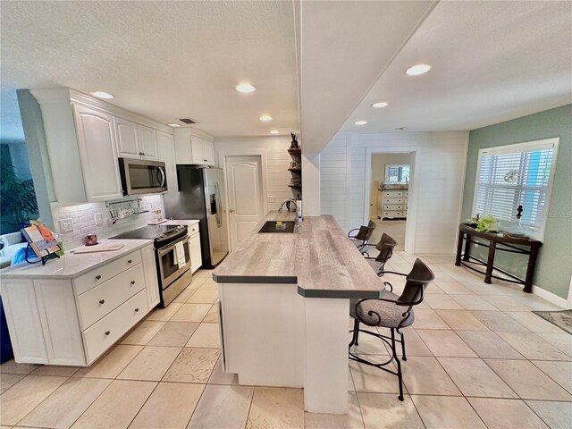 kitchen with kitchen peninsula, sink, white cabinets, stainless steel appliances, and a breakfast bar area