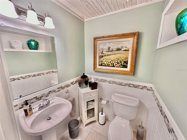 bathroom with decorative backsplash, tile walls, toilet, tile patterned flooring, and sink