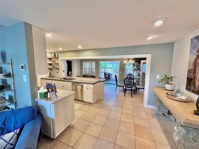 kitchen with light tile patterned flooring, sink, white cabinetry, stainless steel dishwasher, and a chandelier