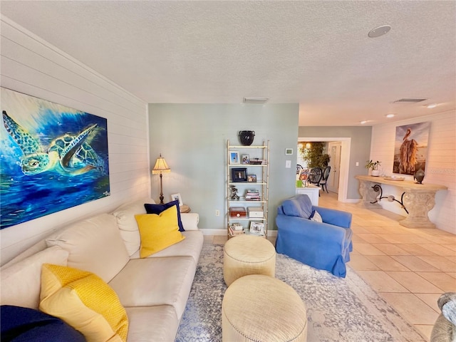 living room with light tile patterned flooring, wood walls, and a textured ceiling