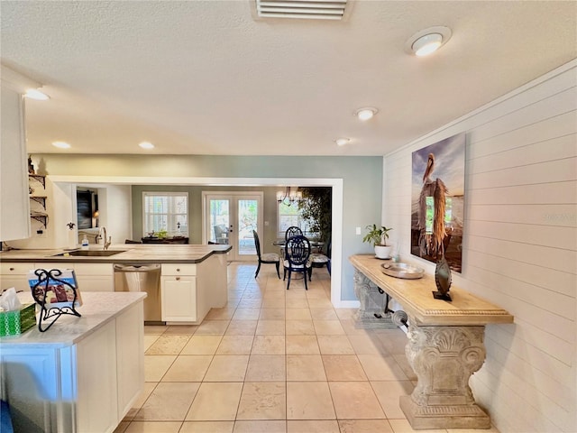 kitchen with a textured ceiling, white cabinetry, dishwasher, light tile patterned flooring, and sink