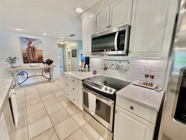 kitchen featuring appliances with stainless steel finishes, backsplash, light tile patterned floors, and white cabinets