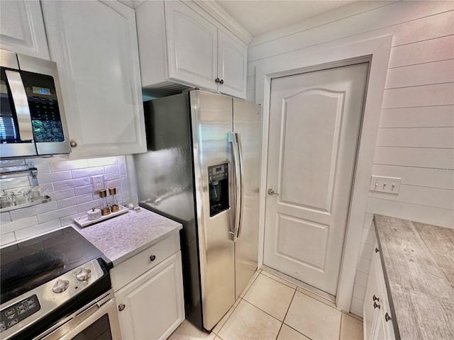 kitchen with decorative backsplash, appliances with stainless steel finishes, light tile patterned flooring, and white cabinetry