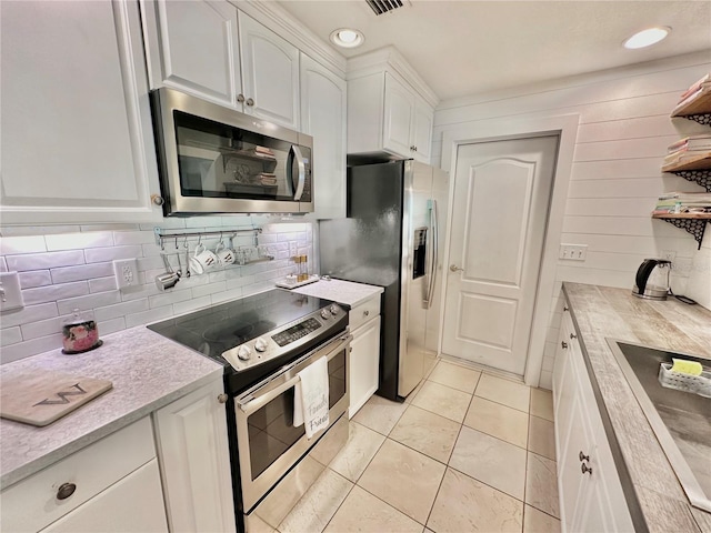 kitchen with decorative backsplash, white cabinets, light tile patterned flooring, and stainless steel appliances