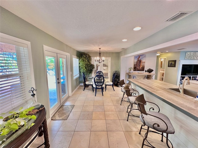 tiled dining area featuring sink, french doors, plenty of natural light, and an inviting chandelier