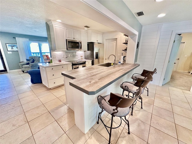 kitchen with stainless steel appliances, decorative backsplash, a kitchen breakfast bar, sink, and kitchen peninsula