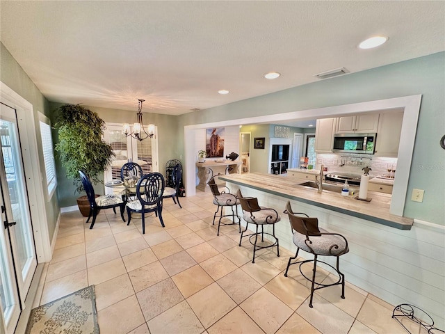 kitchen with backsplash, light tile patterned floors, hanging light fixtures, and a chandelier