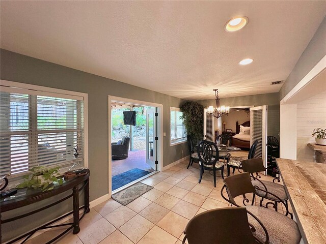 dining space with a textured ceiling, light tile patterned floors, and an inviting chandelier