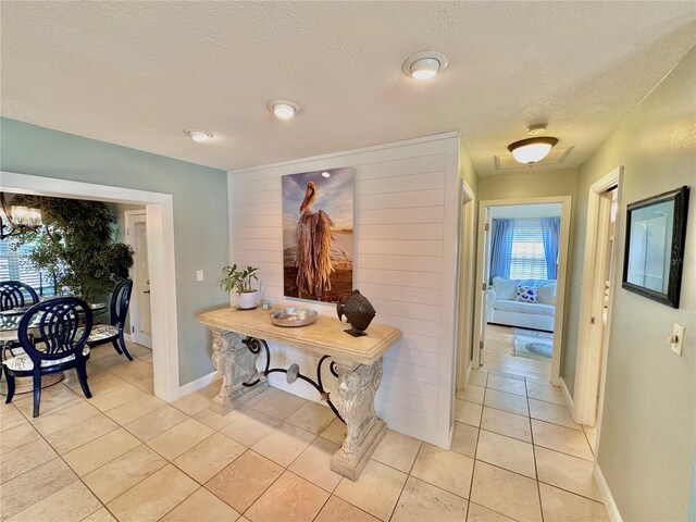 hall featuring light tile patterned floors and a textured ceiling