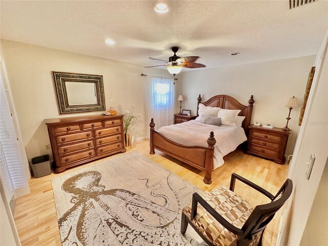 bedroom with ceiling fan, light wood-type flooring, and a textured ceiling