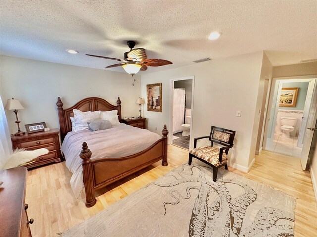 bedroom featuring ceiling fan, a textured ceiling, light wood-type flooring, and connected bathroom