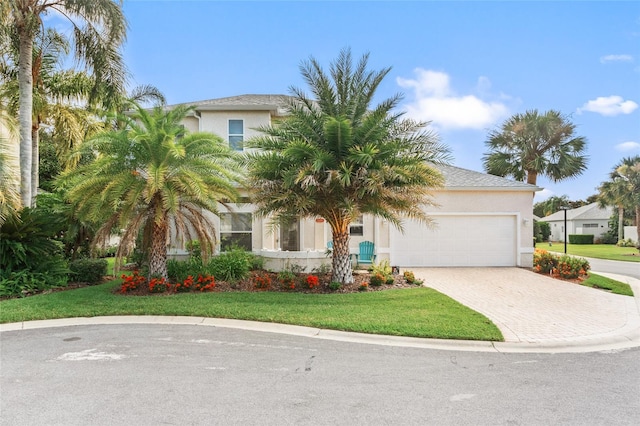 view of front of home featuring an attached garage, a front yard, decorative driveway, and stucco siding