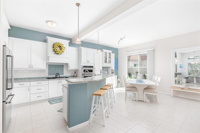 kitchen featuring beam ceiling, hanging light fixtures, appliances with stainless steel finishes, and white cabinets