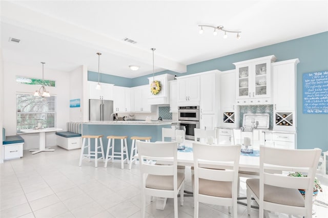 kitchen with appliances with stainless steel finishes, backsplash, light tile patterned floors, a kitchen island, and white cabinetry