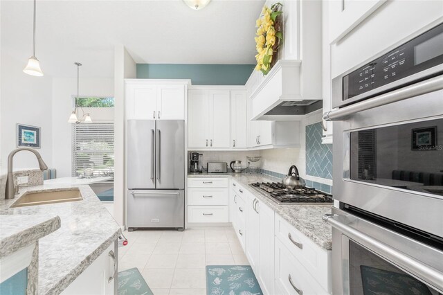 kitchen featuring white cabinetry, sink, custom range hood, appliances with stainless steel finishes, and backsplash