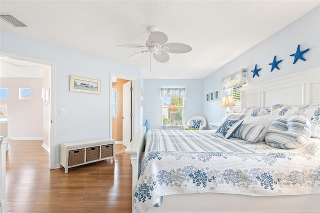 bedroom with a textured ceiling, wood-type flooring, and ceiling fan