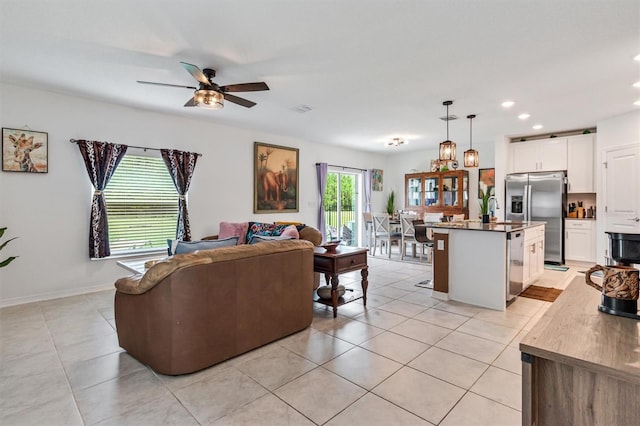 living room featuring light tile patterned floors, sink, and ceiling fan